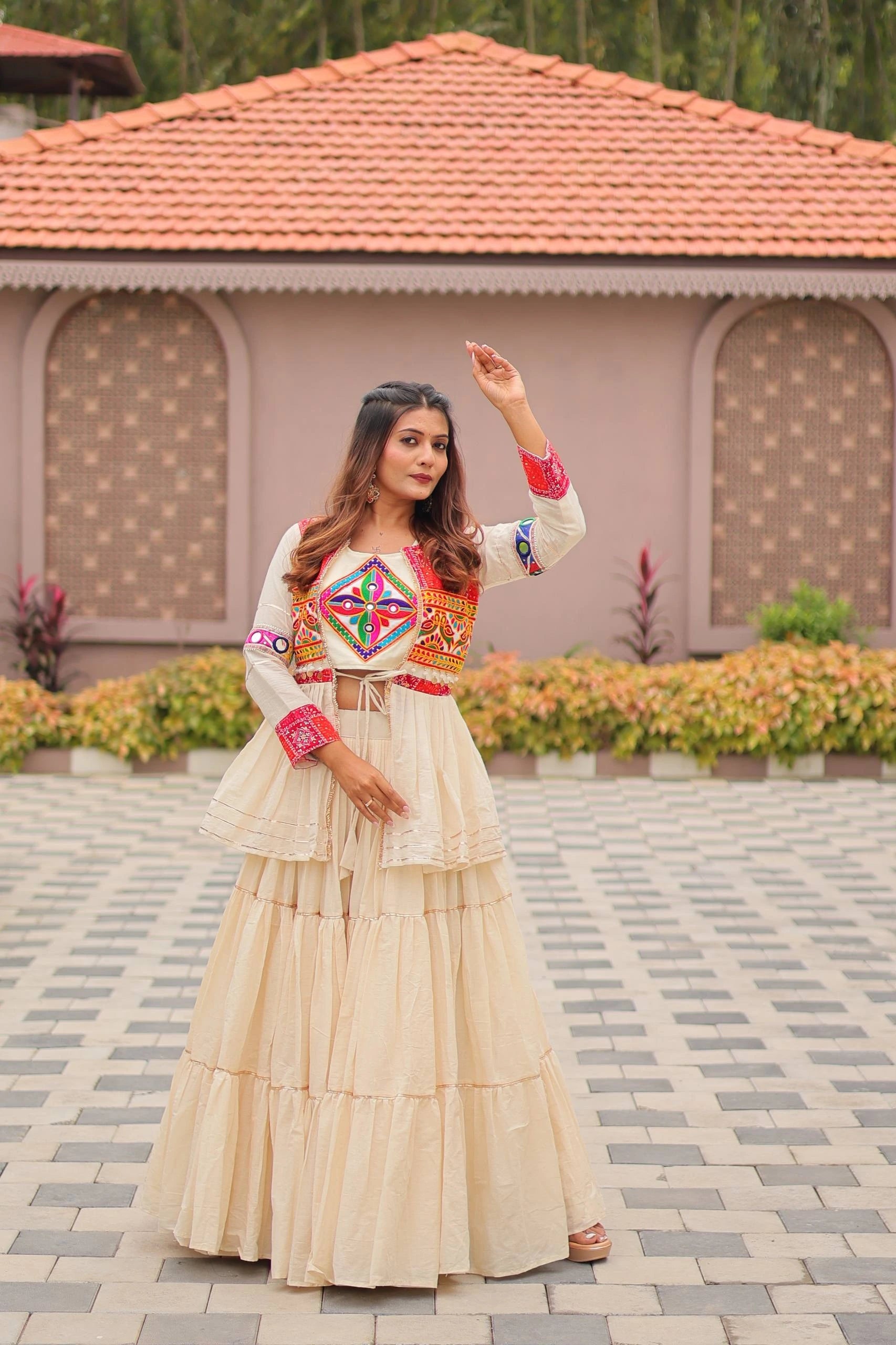 Woman in traditional outfit standing in front of a building with a tiled roof.